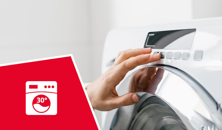Hand öffnet weiße Waschmaschine neben rotem Logo mit 30°C-Waschsymbol