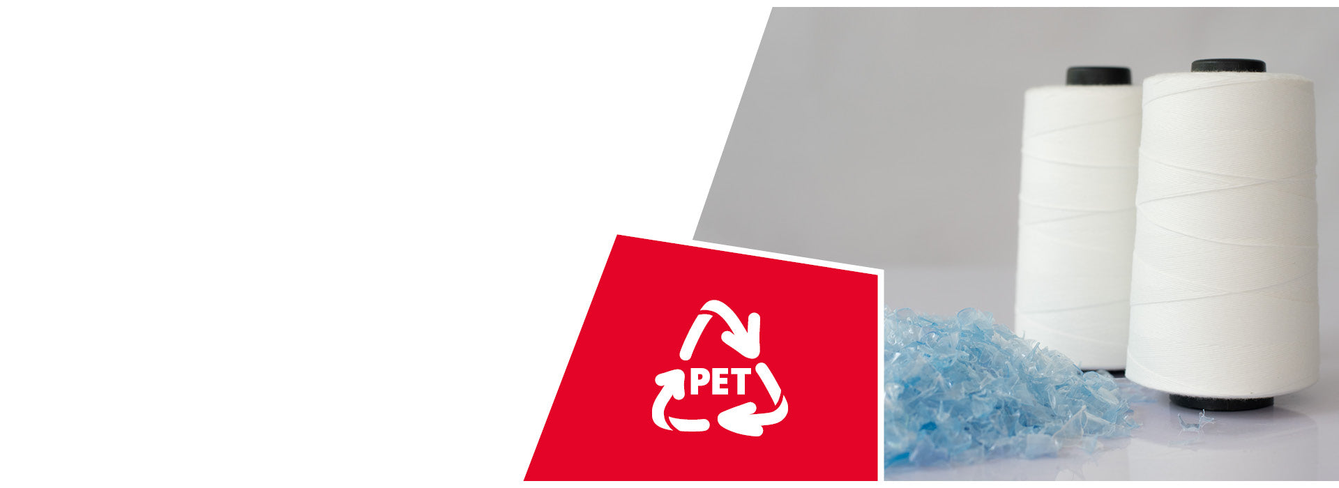 Zwei große weiße Garnspulen stehen nebeneinander auf hellem Untergrund. Davor liegt ein kleiner Haufen bläulicher, recycelter PET-Kunststoffschnipsel. In der unteren linken Bildecke ist ein rotes Feld mit dem weißen Recycling-Symbol und der Aufschrift „PET“ zu sehen – ein Hinweis auf die Wiederverwertung von Kunststoff zu Garn.