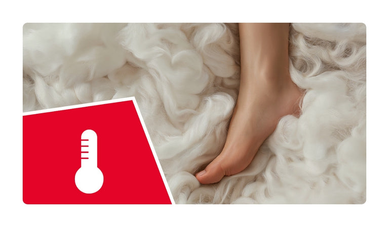 Ein nackter Fuß liegt auf weicher, weißer Wolle und vermittelt ein Gefühl von Wärme und Komfort. In der linken unteren Ecke befindet sich ein rotes Symbol mit einem weißen Thermometer, das auf temperaturregulierende Eigenschaften hinweist.