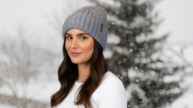 Frau mit grauer Strickmütze in verschneiter Winterlandschaft
