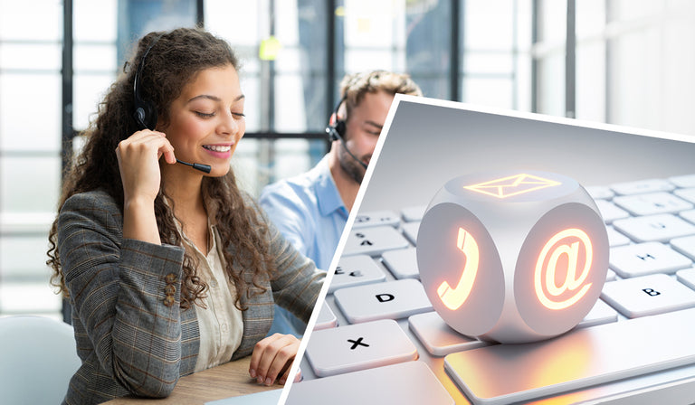 Zwei freundliche Kundenservice-Mitarbeitende mit Headsets sitzen vor einem Laptop in einem hellen Büro. Links vorne eine junge Frau mit lockigem Haar, rechts im Hintergrund ein Mann mit Bart. Im Vordergrund ein schräg eingeblendeter Würfel mit Symbolen für Telefon, E-Mail und @-Zeichen auf einer Computertastatur – als Symbol für Erreichbarkeit und Kundenkontakt.