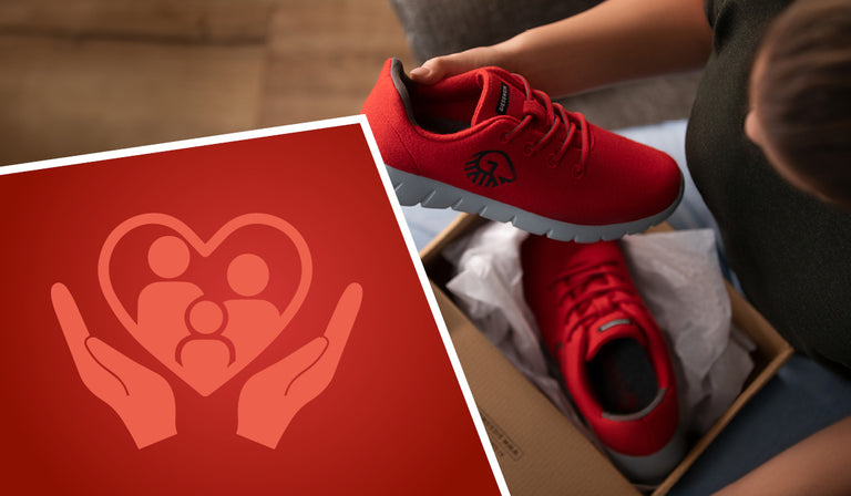 Eine Person hält einen knallroten Woll-Sneaker von Giesswein (Merino Runners) in der Hand und betrachtet ihn liebevoll. Der Schuh liegt in einem offenen Schuhkarton auf dem Schoß der sitzenden Person. Links im Bild ist ein rotes Icon eingeblendet, das ein Herz mit stilisierter Familie und schützenden Händen zeigt – Symbol für Fürsorge und Familienfreundlichkeit.