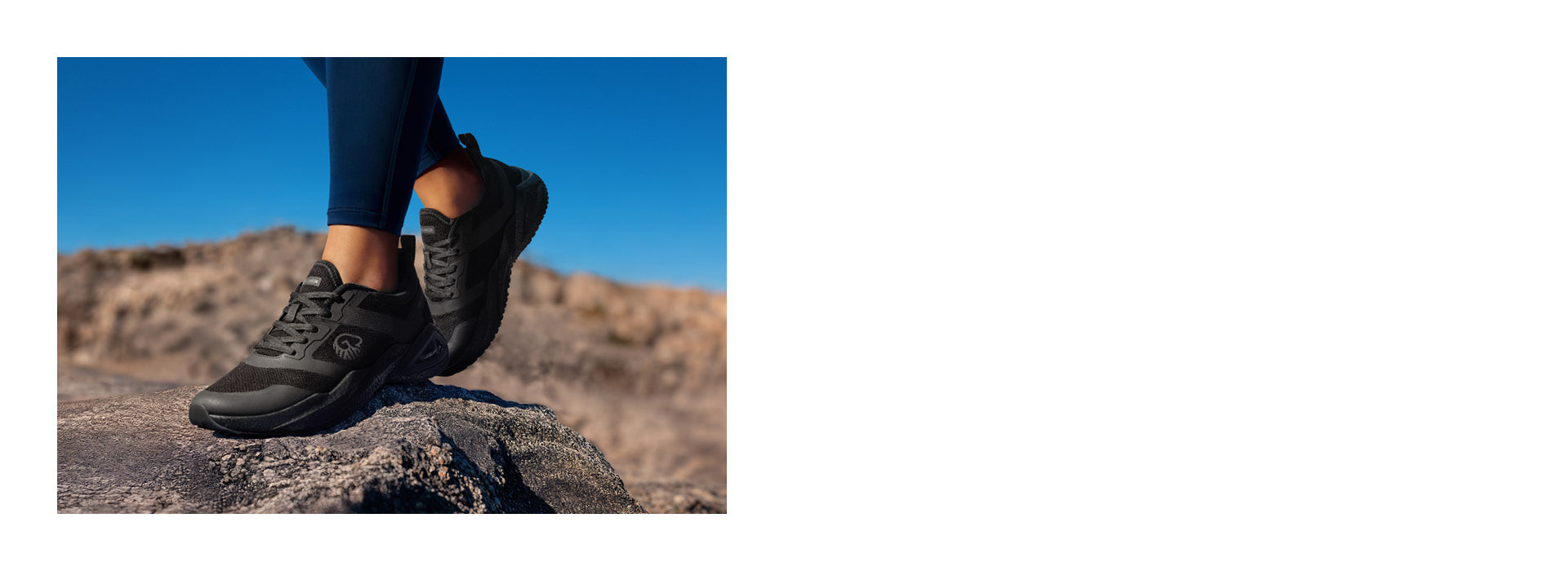 Person steht auf einem Felsen in einer felsigen, trockenen Landschaft unter klarem, blauem Himmel. Sie trägt schwarze Trail-Schuhe mit robuster Sohle (Wool Peak von Giesswein) und dunkler Sportleggings – bereit für eine Wanderung oder Outdoor-Aktivität.