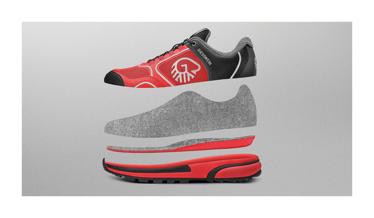 Darstellung eines roten Sportschuhs der Marke Giesswein (Wool Cross X) in aufgeschnittener, explodierter Ansicht. Die einzelnen Schichten des Schuhs sind übereinander schwebend angeordnet, von oben nach unten: äußere Textilhülle mit Giesswein-Logo, graue Innenschicht aus Merinowolle, gepolsterte Einlegesohle und robuste Außensohle in Rot-Schwarz mit Profil. Der Hintergrund ist neutral grau. Die Abbildung visualisiert den Aufbau und die Materialien des Schuhs.